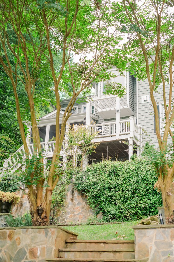The AirBnB lake house Tiffany's family booked and used as their getting-ready suites; gray multi-story home surrounded by lush green landscaping and brown stone.