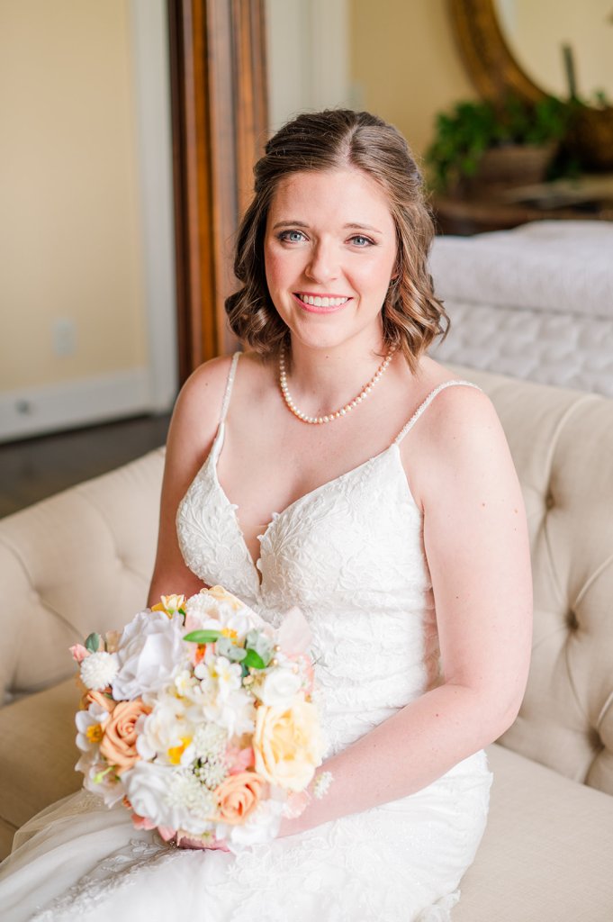 Photo of Tiffany on her wedding day, seated on a tufted couch holding her wedding bouquet